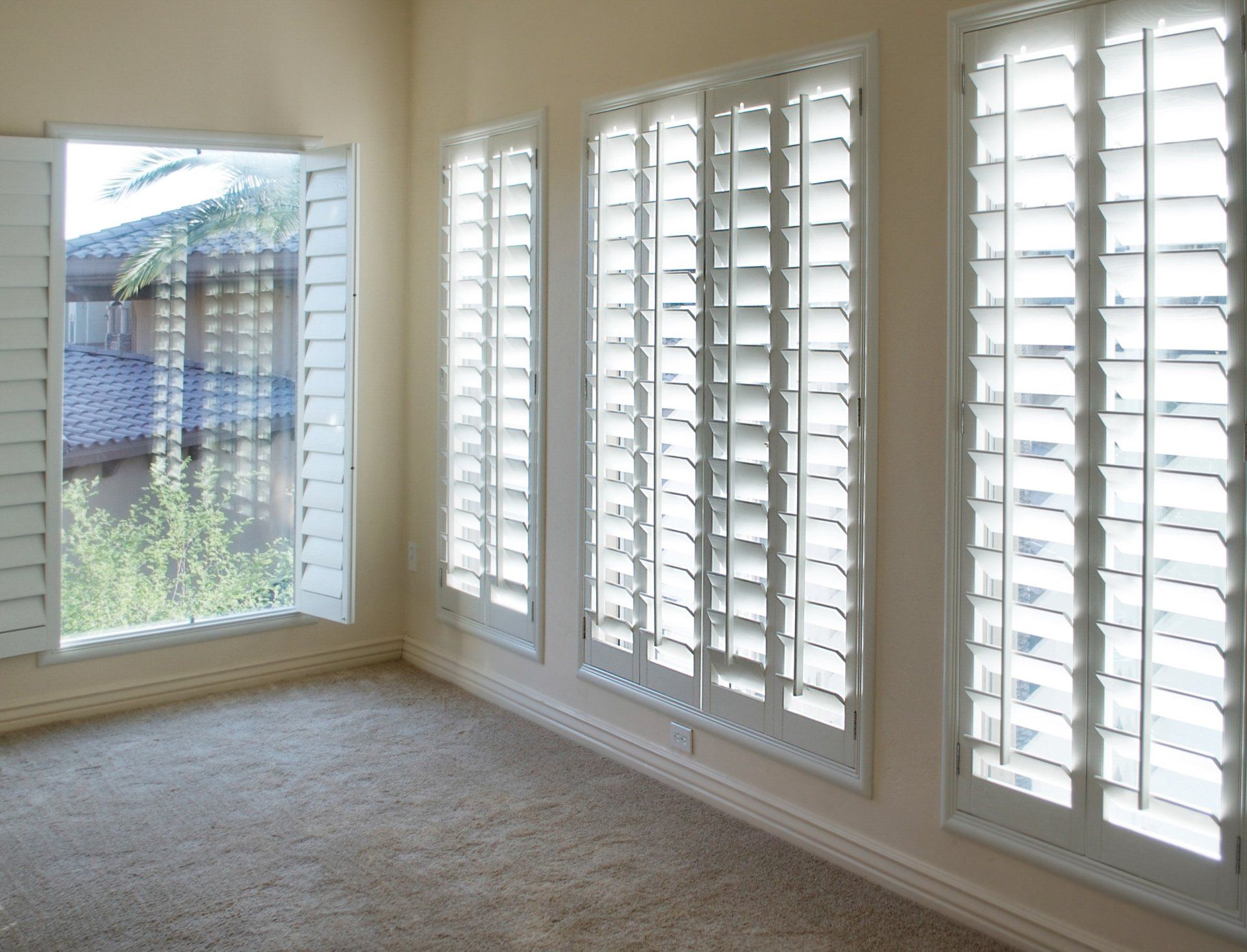 Full length plantation shutters, open in empty carpeted loungeroom.