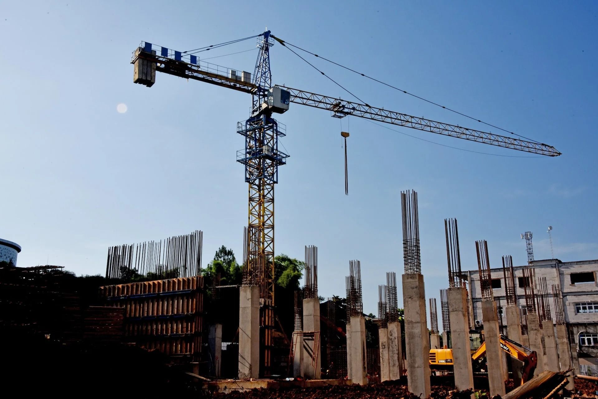 Construction site with a tall crane, partially built structure, and blue sky at sunset