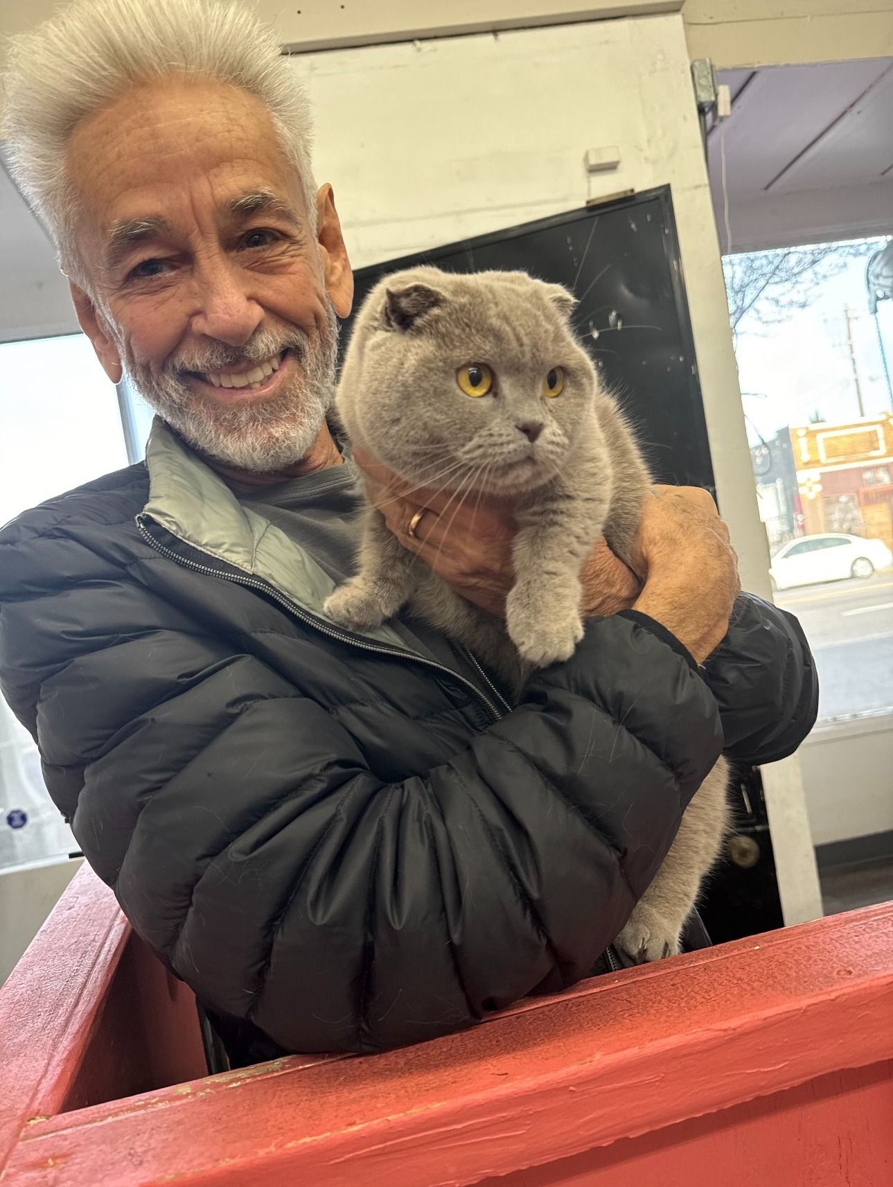 A man is holding a cat in his arms and smiling.