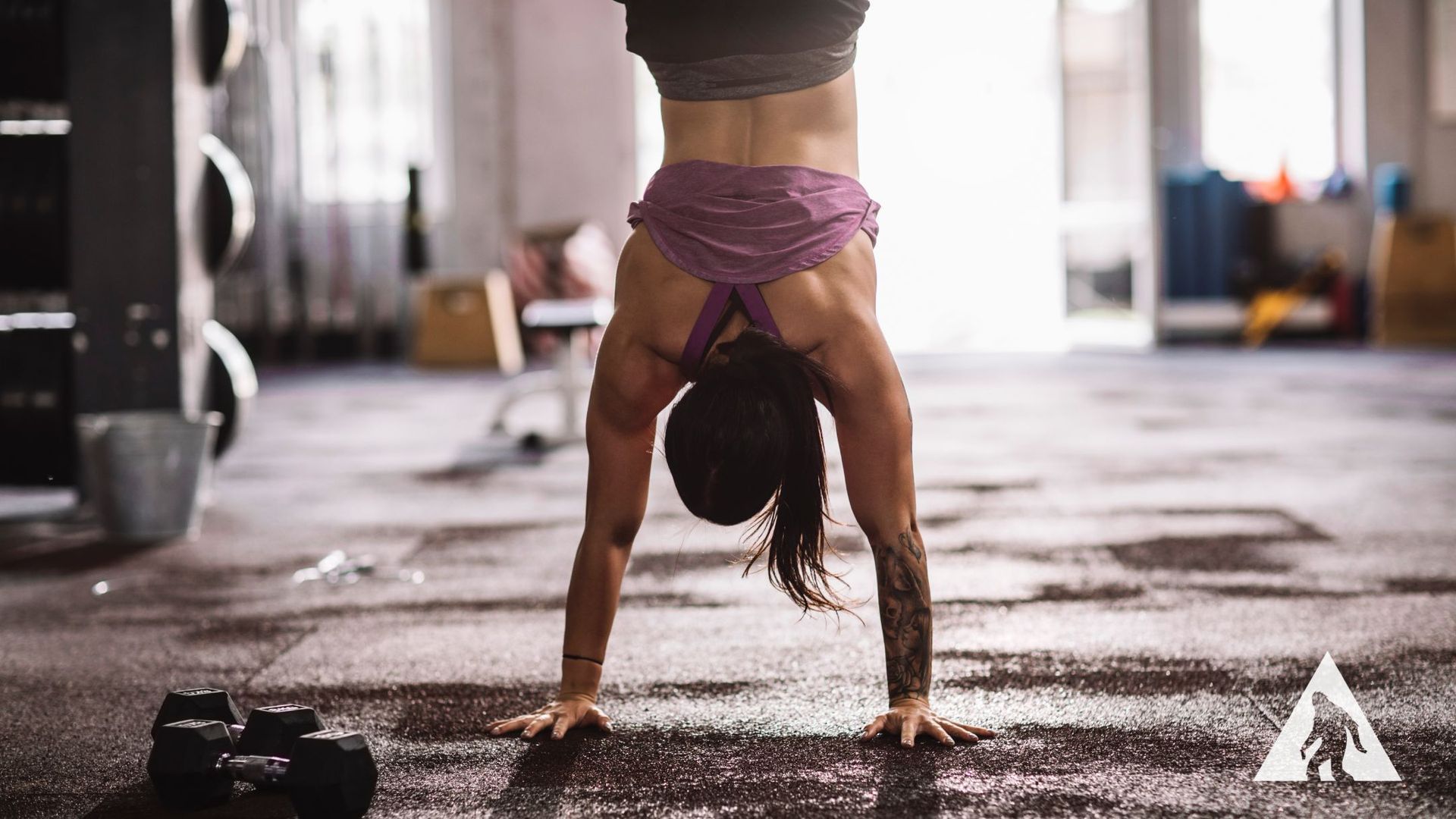 A woman is doing a handstand in a gym.