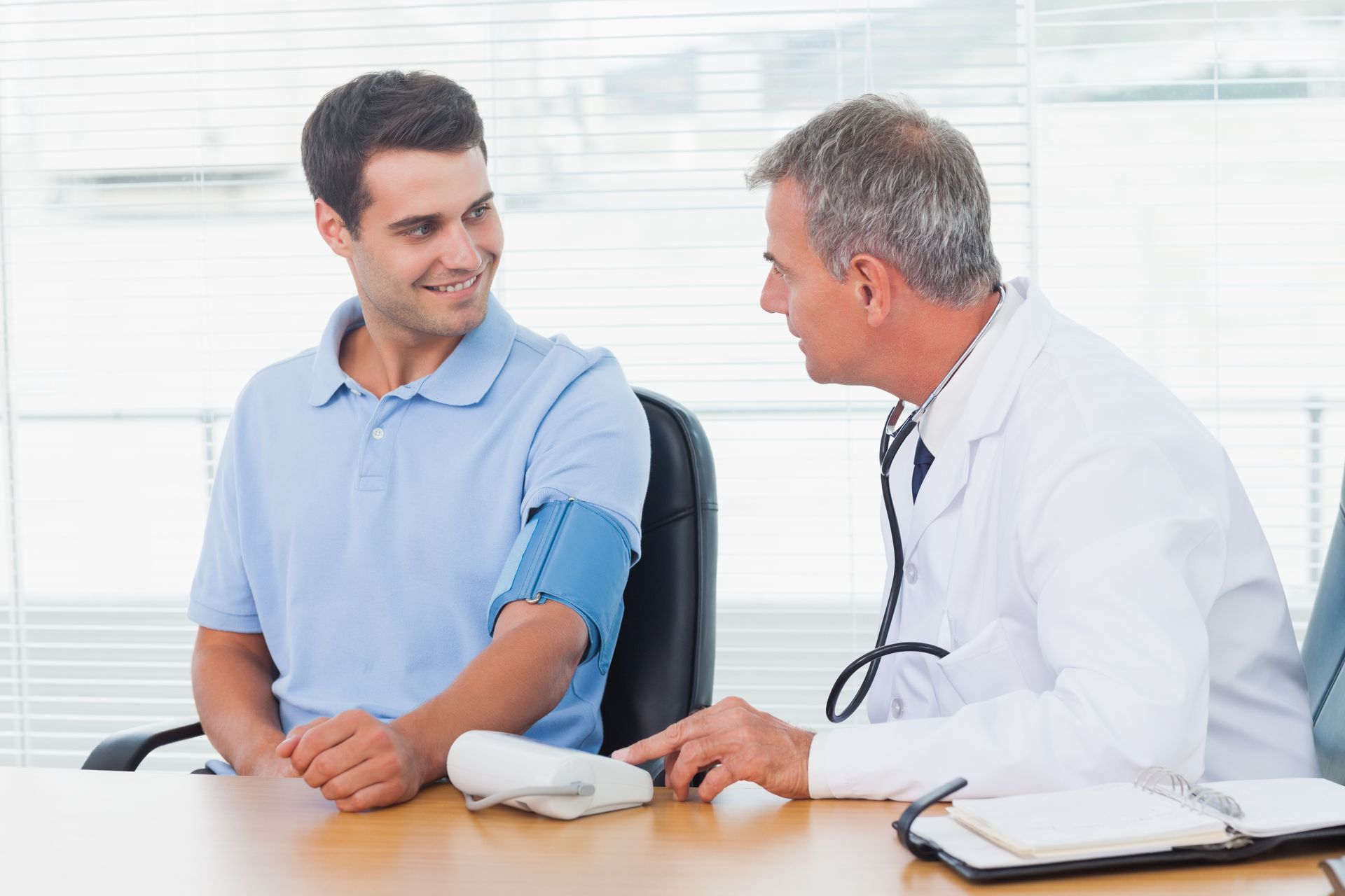 A doctor measures a male patient’s blood pressure during a routine physical exam.
