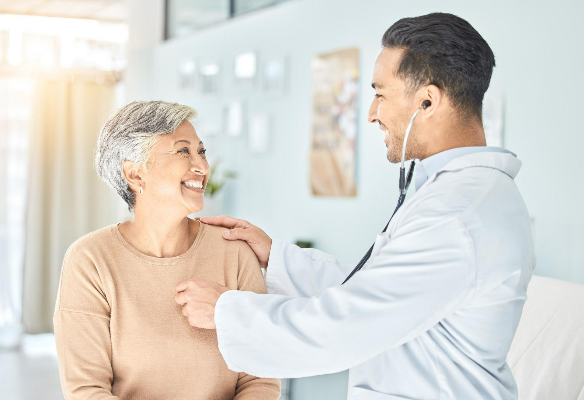 A woman patient smiling at her doctor while getting checked. 