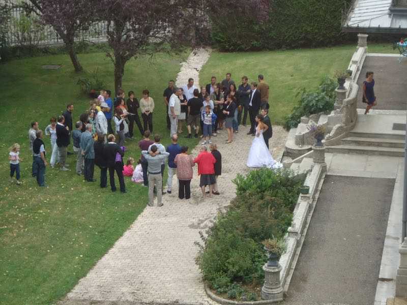 Een groep mensen is verzameld in een park, waaronder een bruid en bruidegom