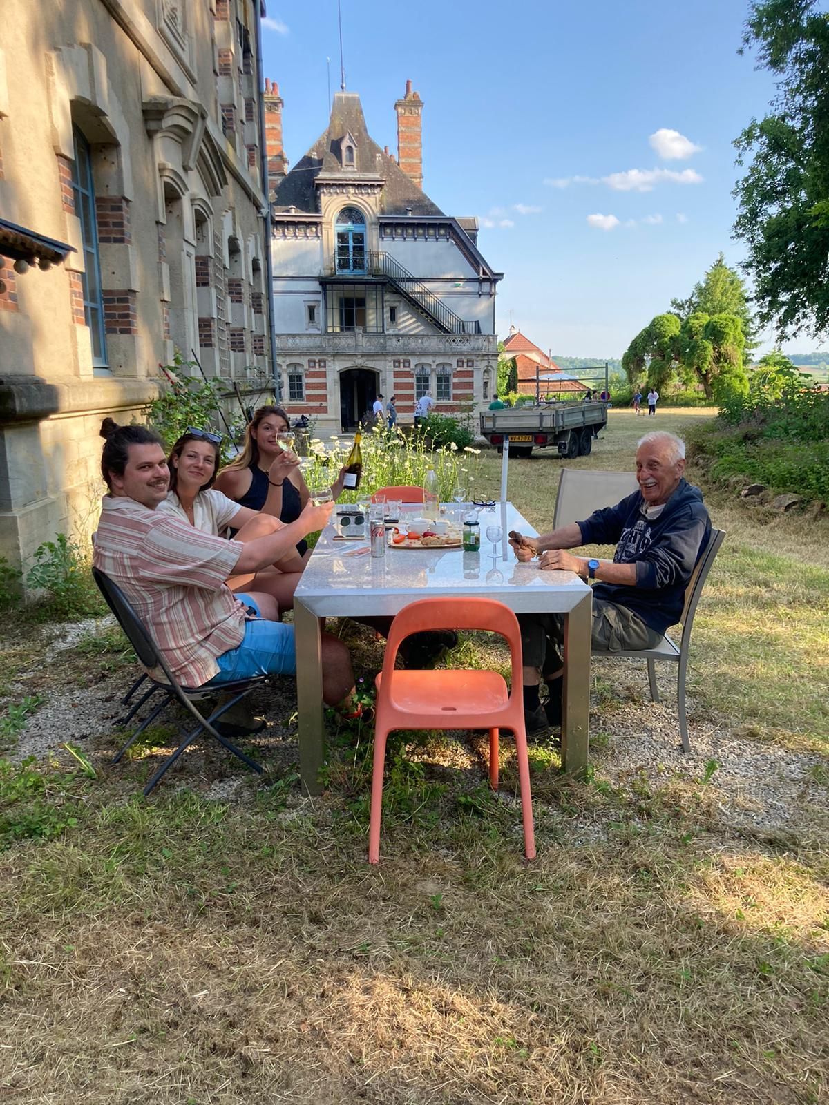 Een groep mensen zit rond een tafel voor een gebouw.