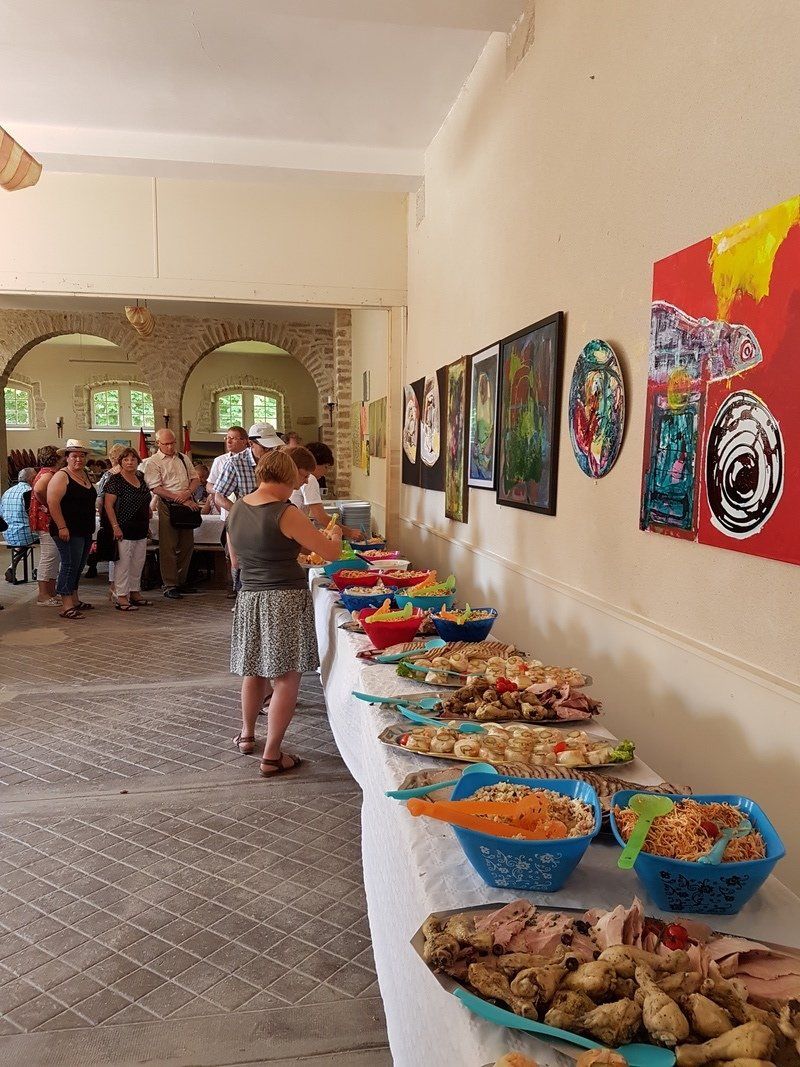Een groep mensen staat rond een buffet tafel vol met eten