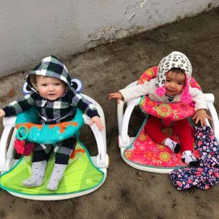 Two Babies Are Sitting in High Chairs on the Ground