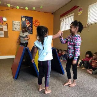 Two Little Girls Are Standing Next to Each Other in a Room