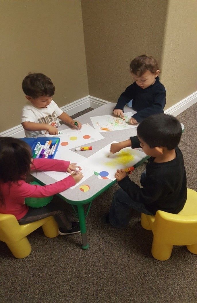 A group of children are sitting around a table drawing.