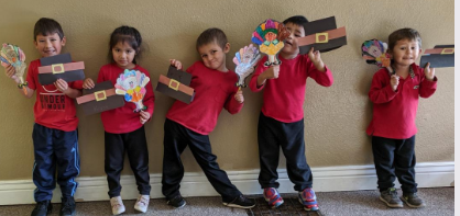 A group of children are standing next to each other holding paper crafts.