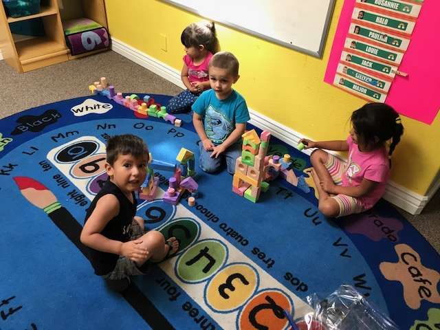 A group of children are sitting on the floor playing with toys
