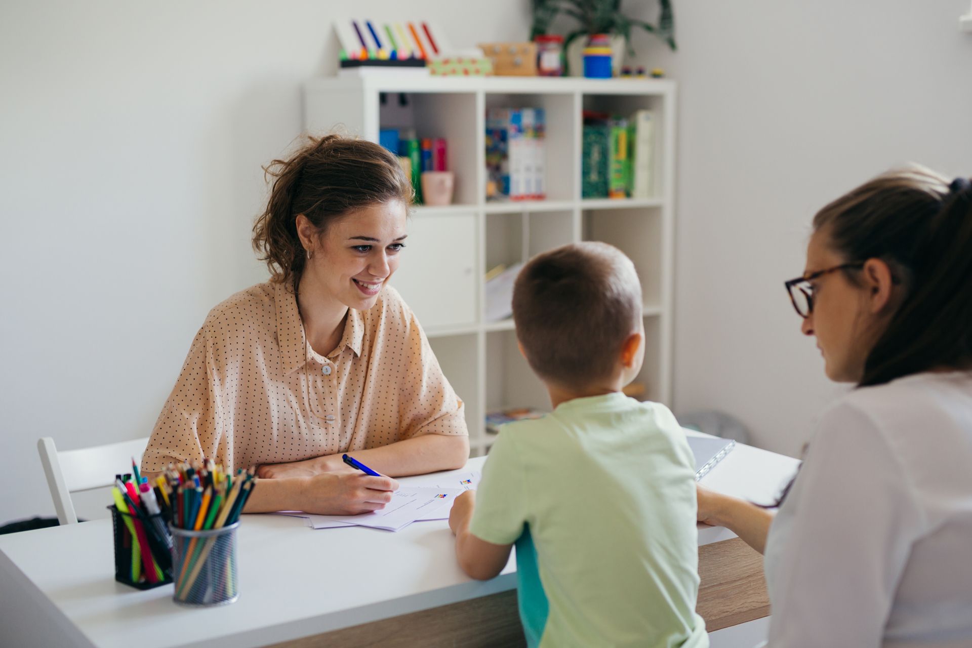 A Woman is Sitting at a Table With a Child and a Woman