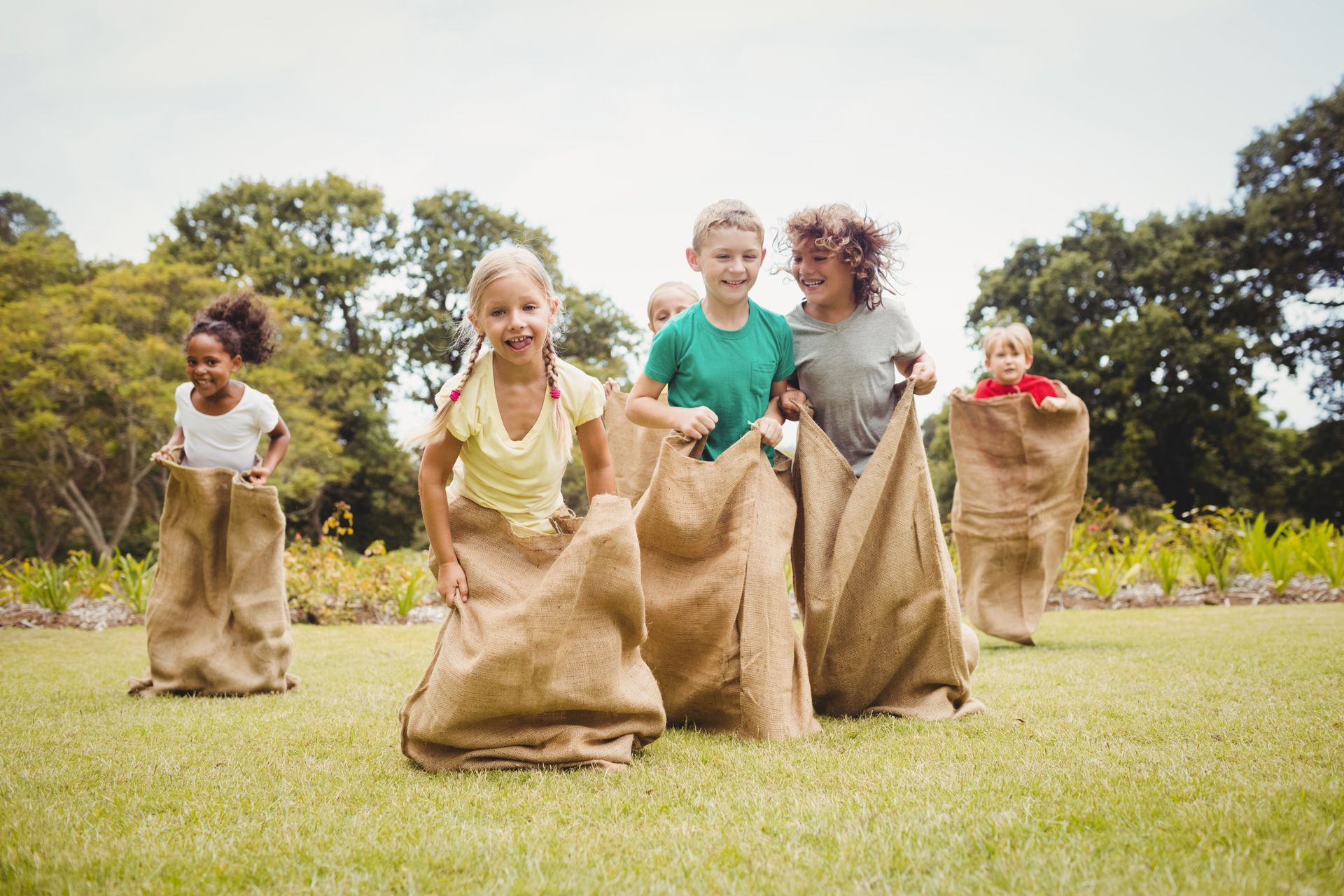 A Group of Children Are Playing a Sack Race in a Park.