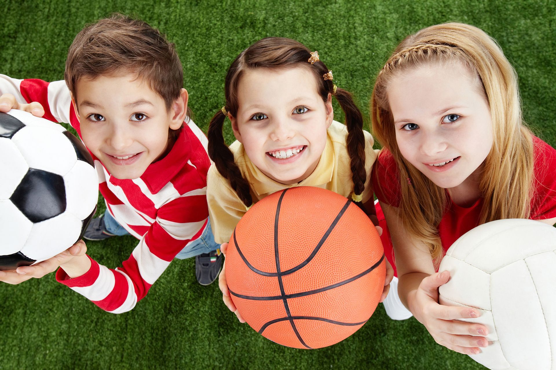 Three Children Are Holding Soccer , Basketball and Volleyball Balls