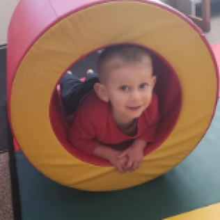 A Little Boy is Crawling Through a Red and Yellow Circle