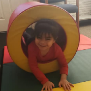 A Little Girl is Crawling Through a Yellow and Red Circle