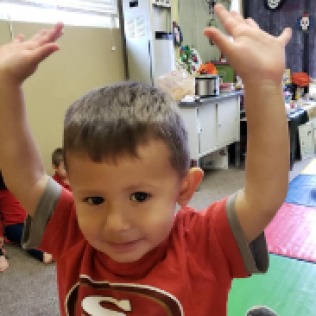A Young Boy Wearing a Red Shirt With the Letter S on It