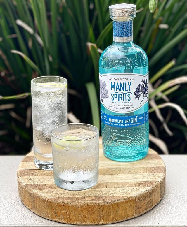 Manly Spirits Gin Is Sitting on A Wooden Cutting Board Next to A Glass of Gin — Roundabout Inn in Gloucester, NSW