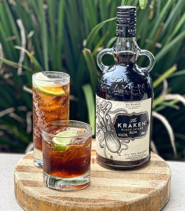 A Bottle of Rum Is Sitting on A Wooden Cutting Board Next to Two Glasses of Rum — Roundabout Inn in Gloucester, NSW