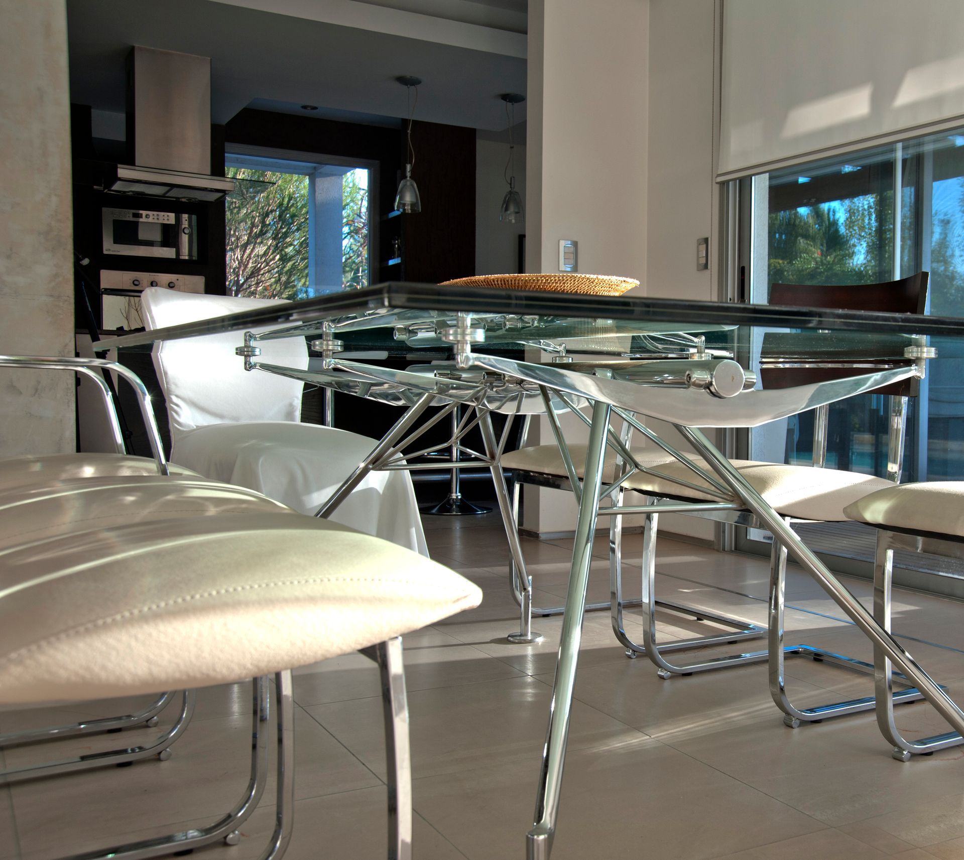Comedor con mesa de cristal, sillas cromadas y luz natural.