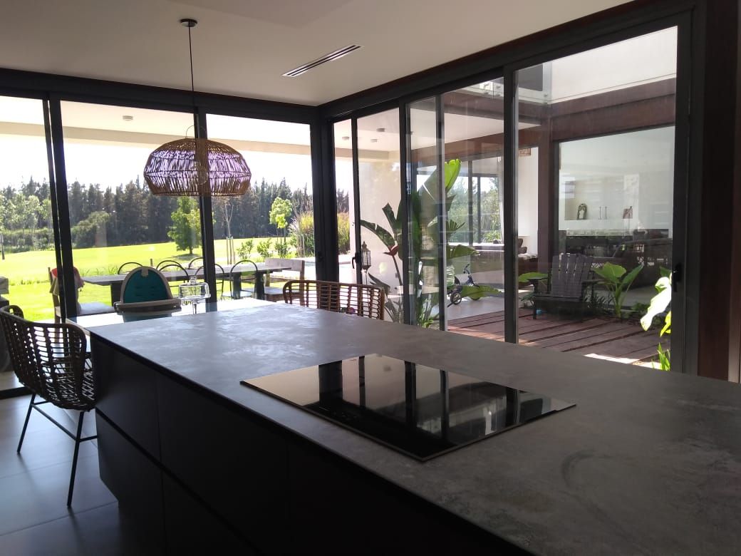 Cocina moderna con isla y anafe, con vista a patio exterior y árboles.