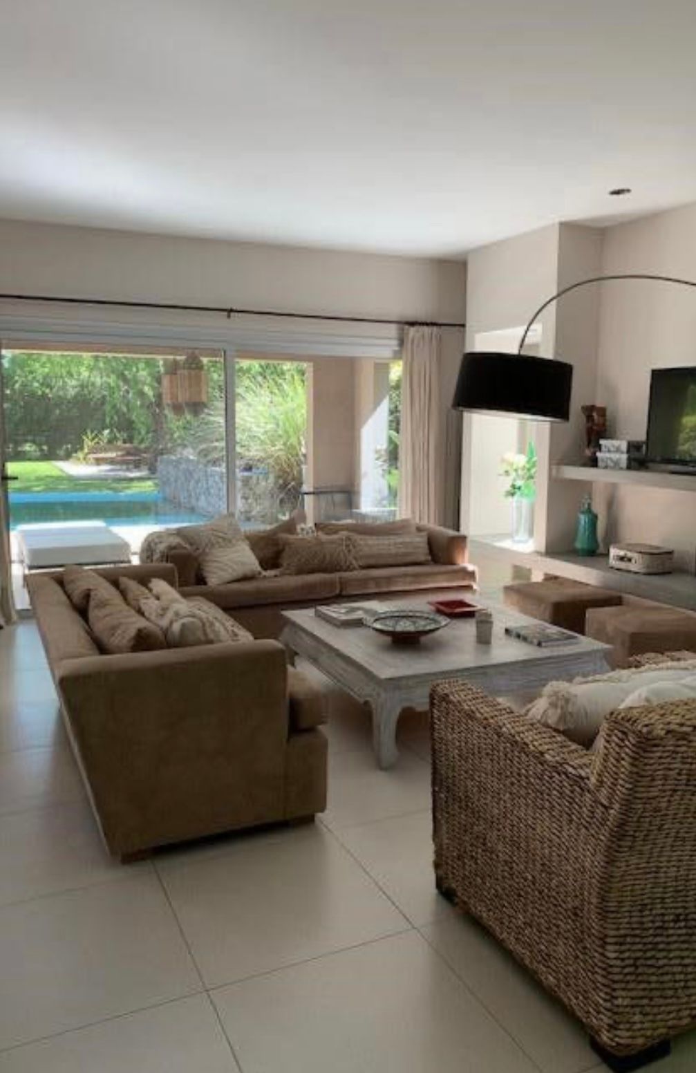 Salón con sofás y sillones, junto a una piscina.