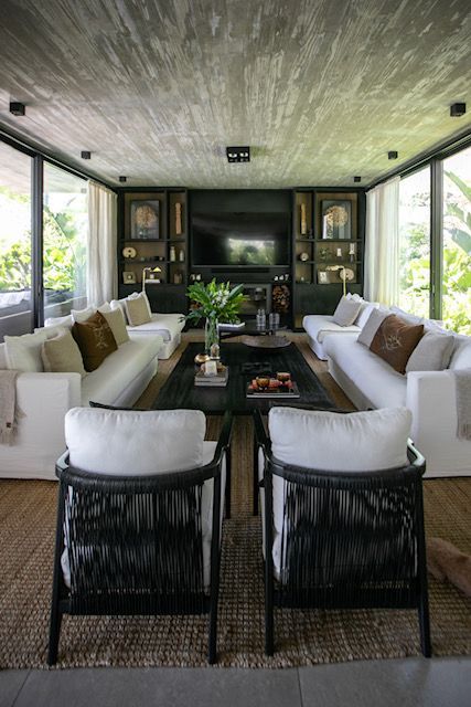 Sala de estar moderna con sofás blancos, detalles en negro y sillones tejidos.