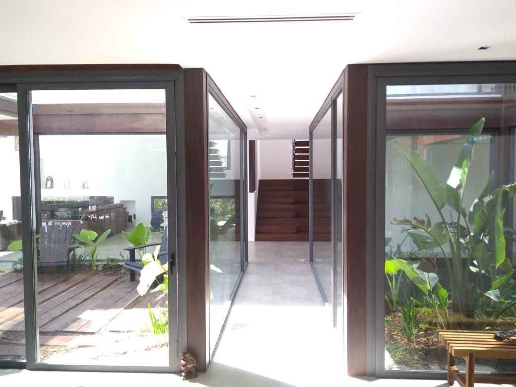 Pasillo con paredes de cristal, con vista a zonas exteriores con plantas y escalera.