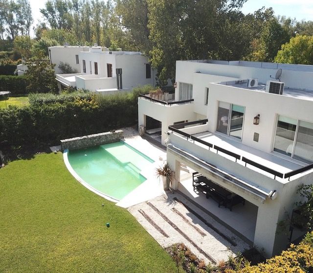 Casas blancas modernas con piscina y césped. Entorno soleado al aire libre.