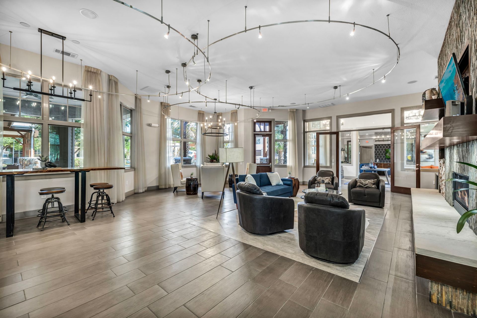 Spacious, modern living room with couches, a bar, and track lighting; neutral colors.
