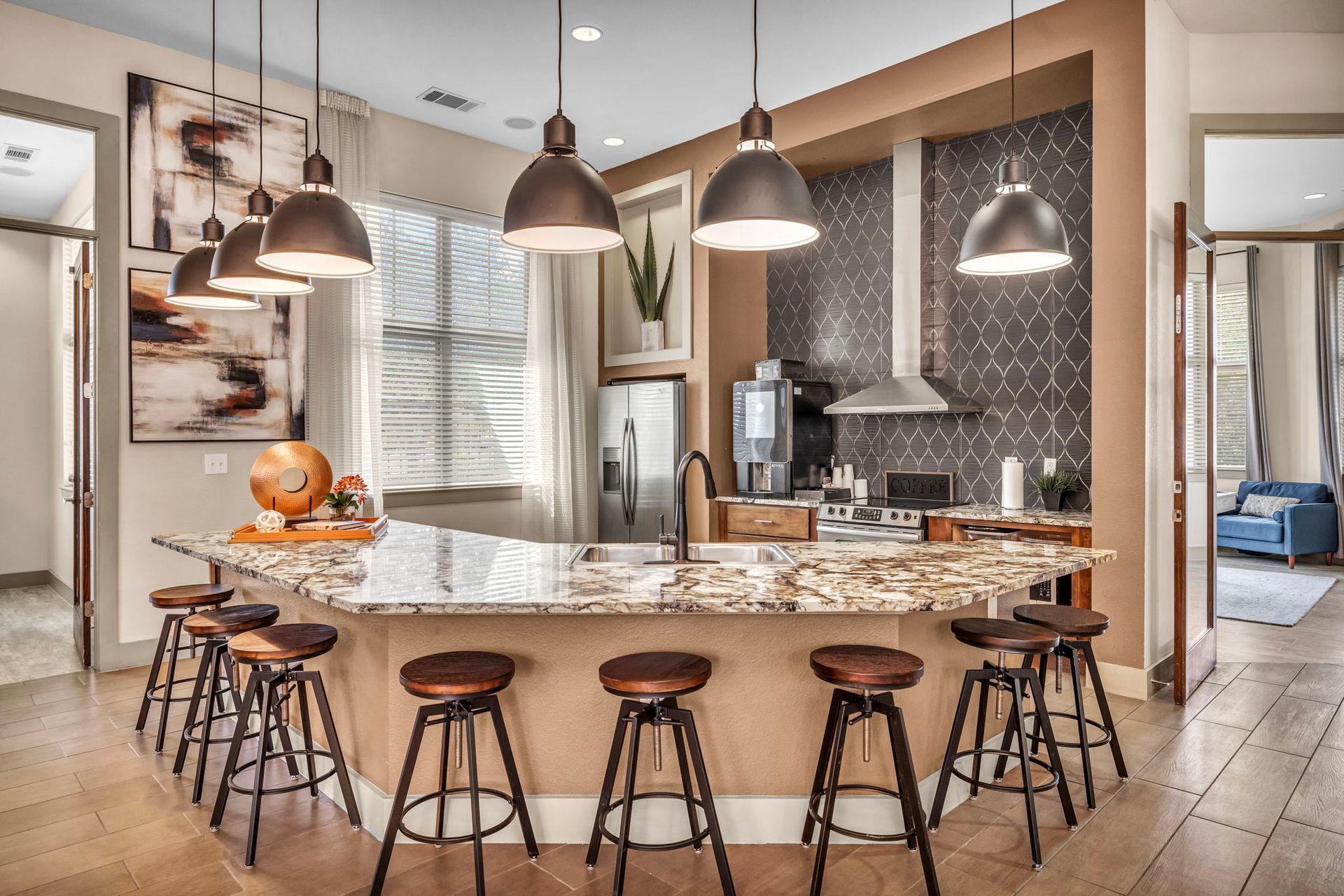Kitchen with granite countertop island, pendant lights, and bar stools. Neutral colors.