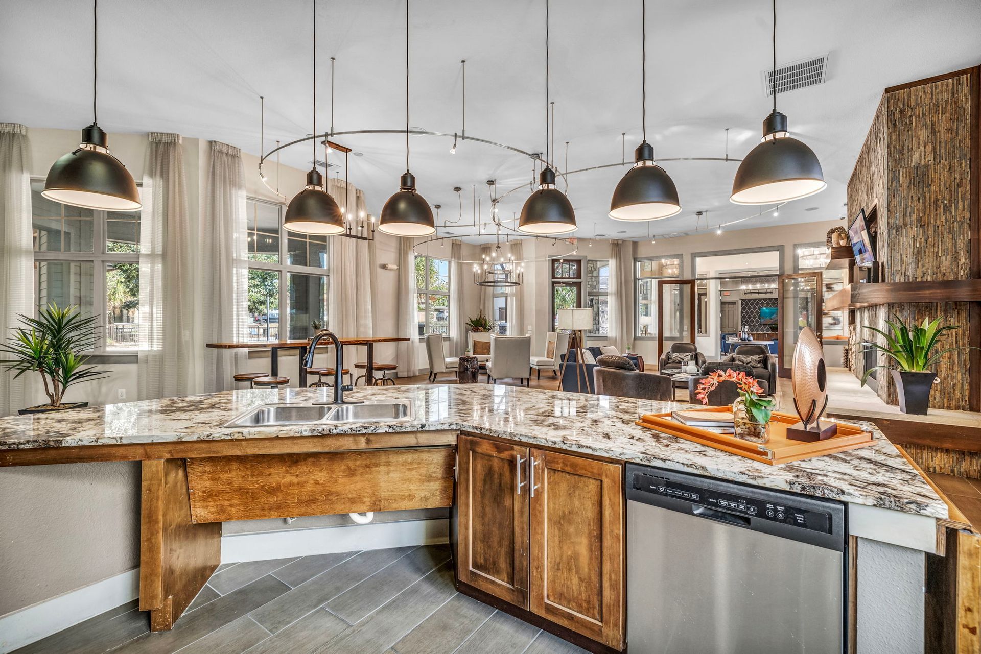 Kitchen with granite countertops, wood cabinets, and pendant lights, adjacent to a living room.