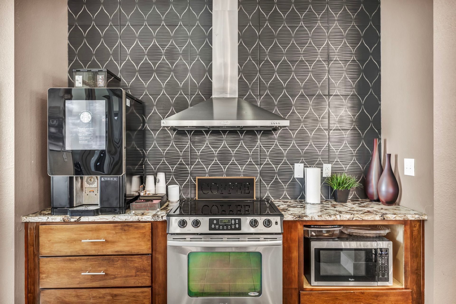 Kitchen area with coffee machine, stove, microwave, and decorative backsplash.