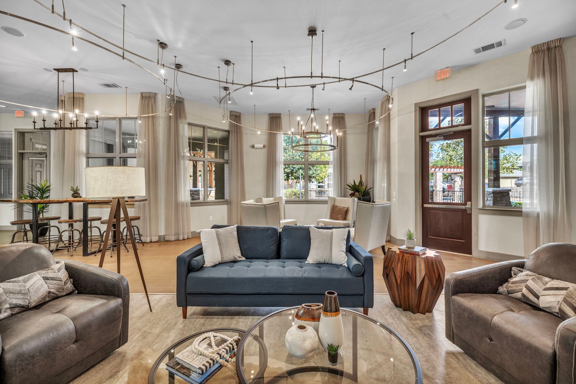 Lounge area with sofas, round coffee table, windows, and modern lighting.