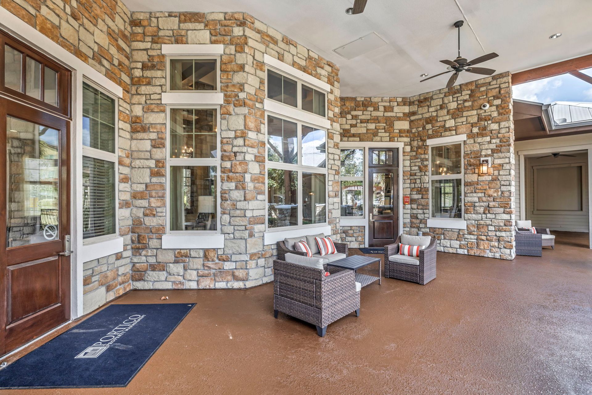 Stone exterior patio with seating, windows, and brown door.
