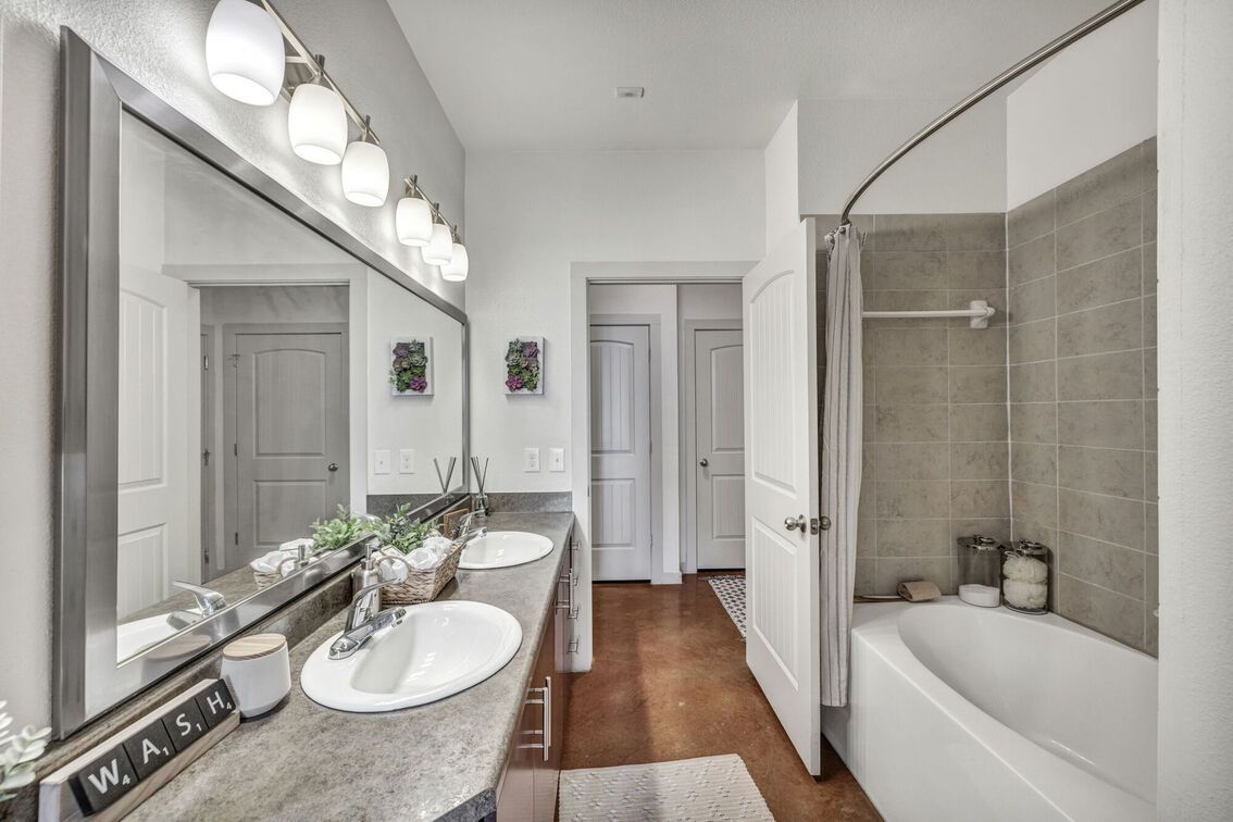 Walk-in closet with white shelves, hanging clothes, and decorative items.