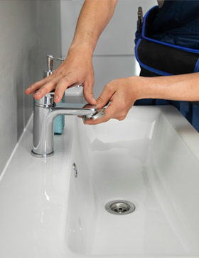 Person installing a chrome faucet on a white sink.