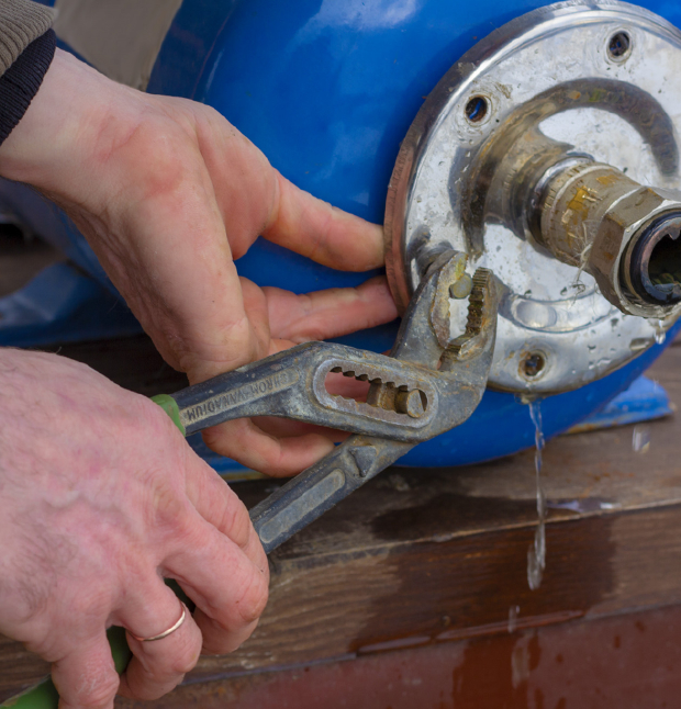 Person using pliers to work on a leaking water tank.