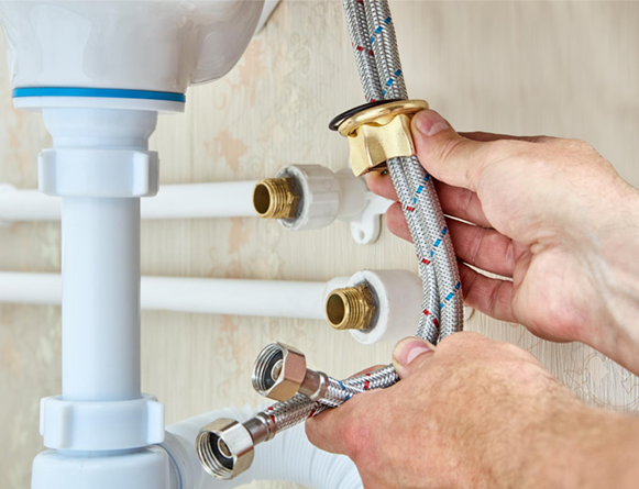 Hands connecting braided water supply lines to plumbing fixtures.