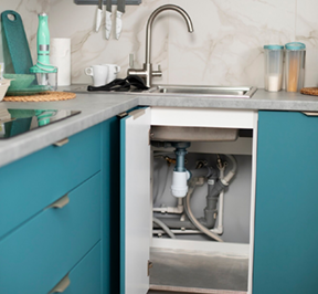 Kitchen sink with visible plumbing and turquoise cabinets.
