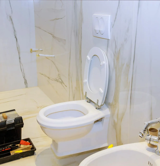 Toilet in a bright bathroom, lid open. Toolbox on floor.