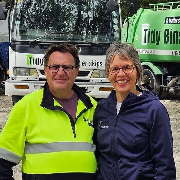 Lynnette and Kevin from Tidy Bins in front of two of their trucks.