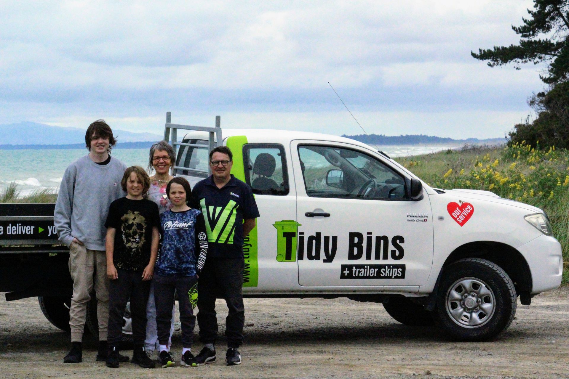 A family standing in front of a truck that says Tidy Bins