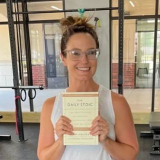 A woman is holding a book titled the daily stoic
