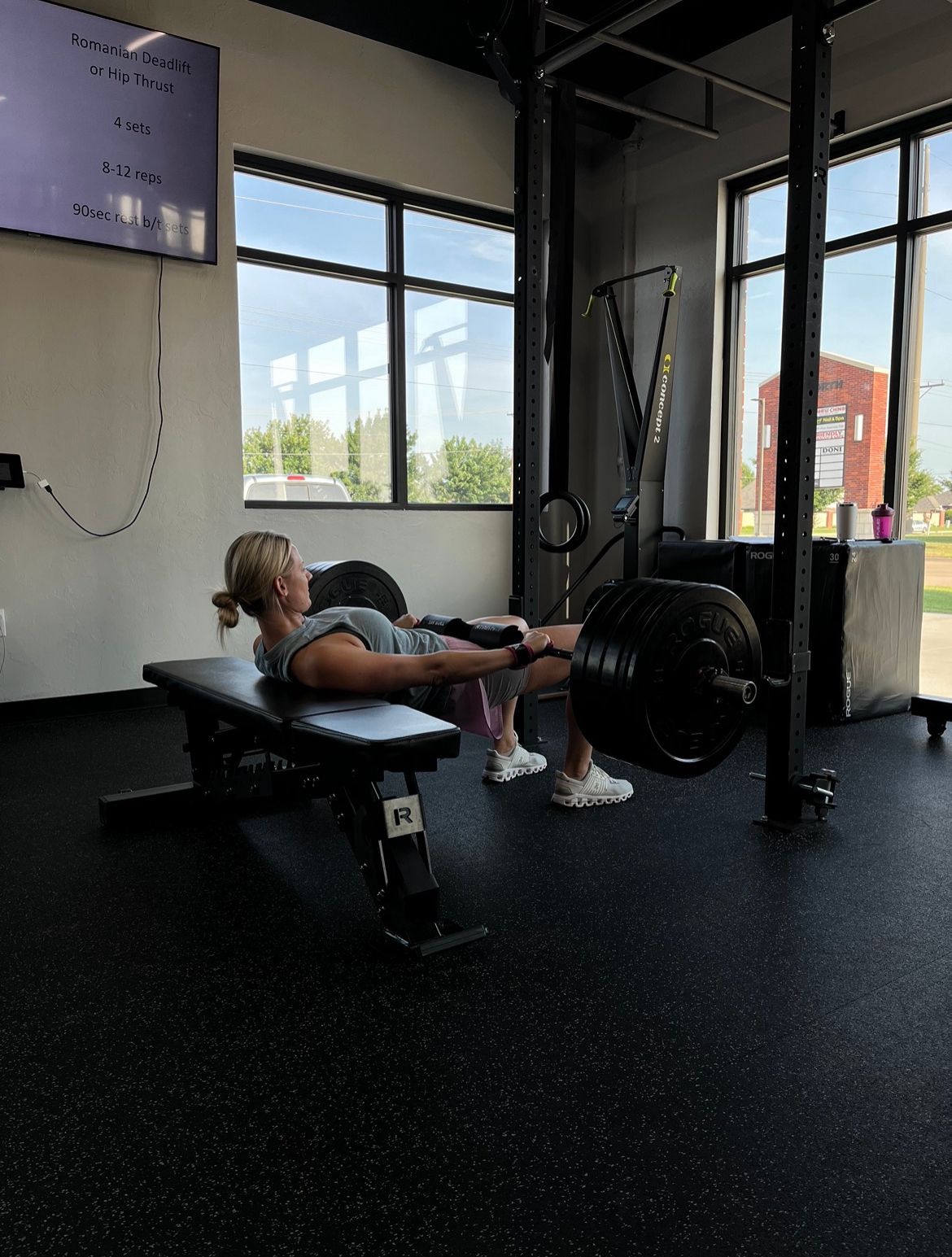 A woman is doing squats on a bench in a gym.
