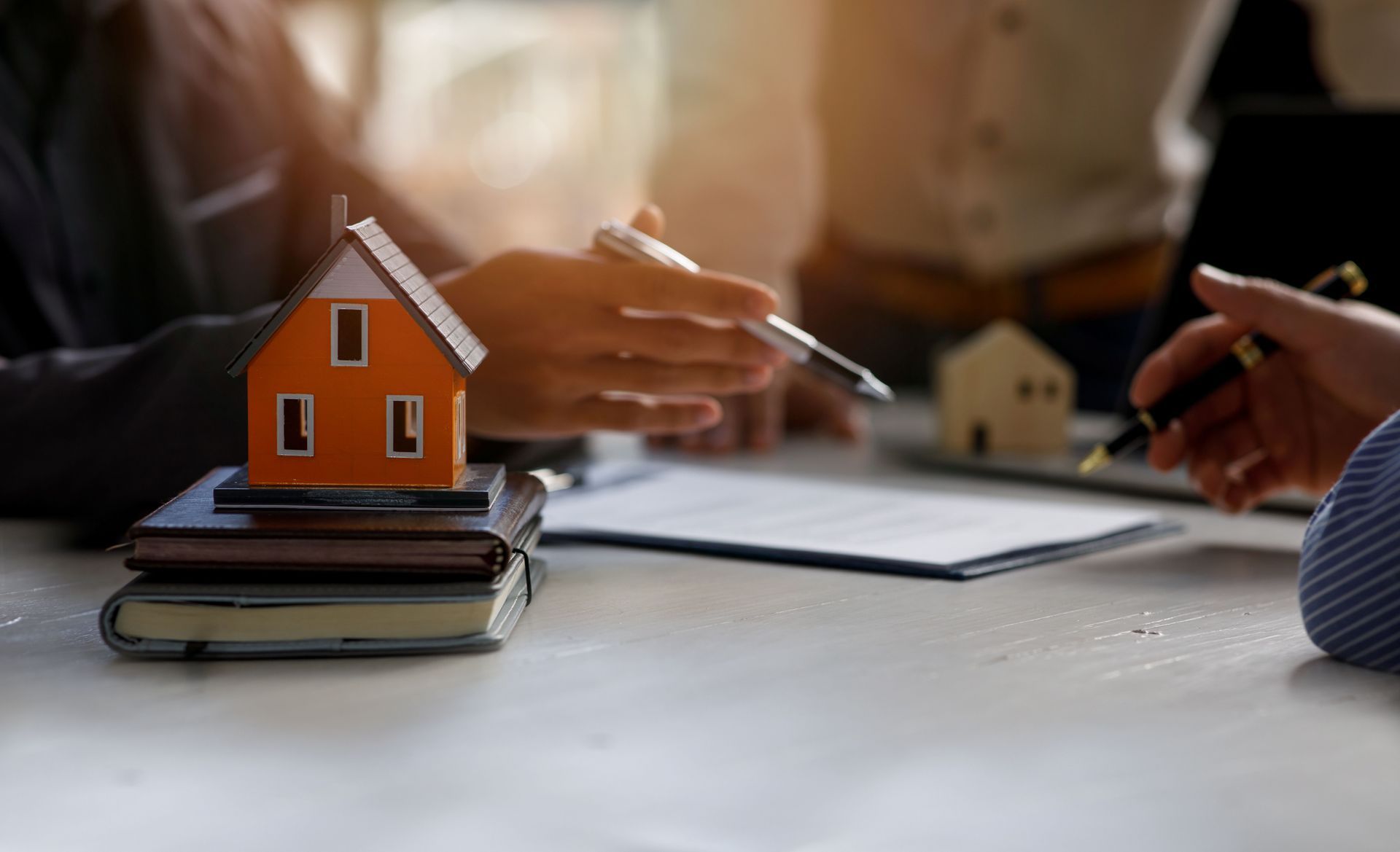 Real state planning lawyer reviewing property documents with a miniature house model on the desk.