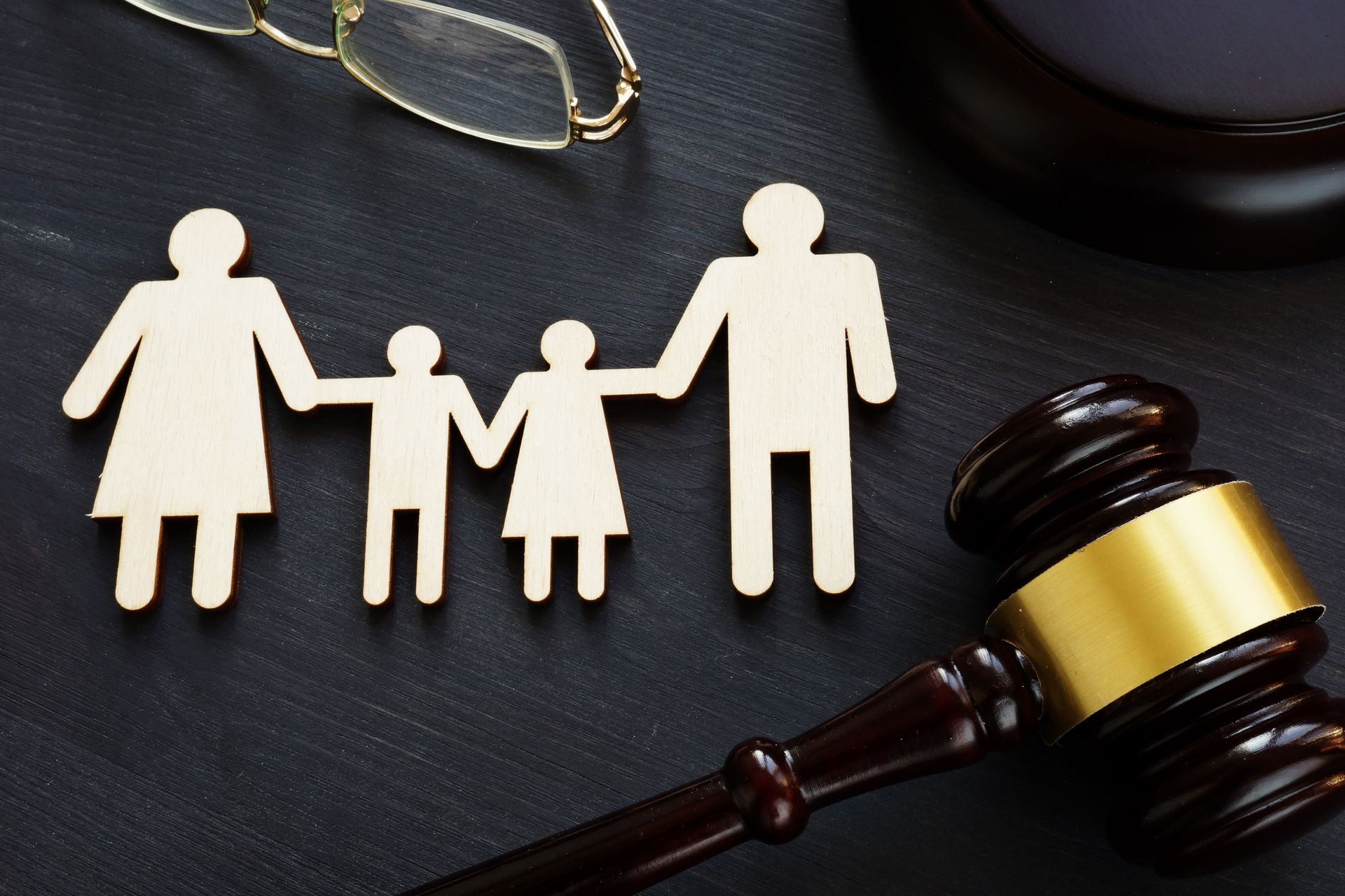 A wooden family holding hands next to a wooden gavel