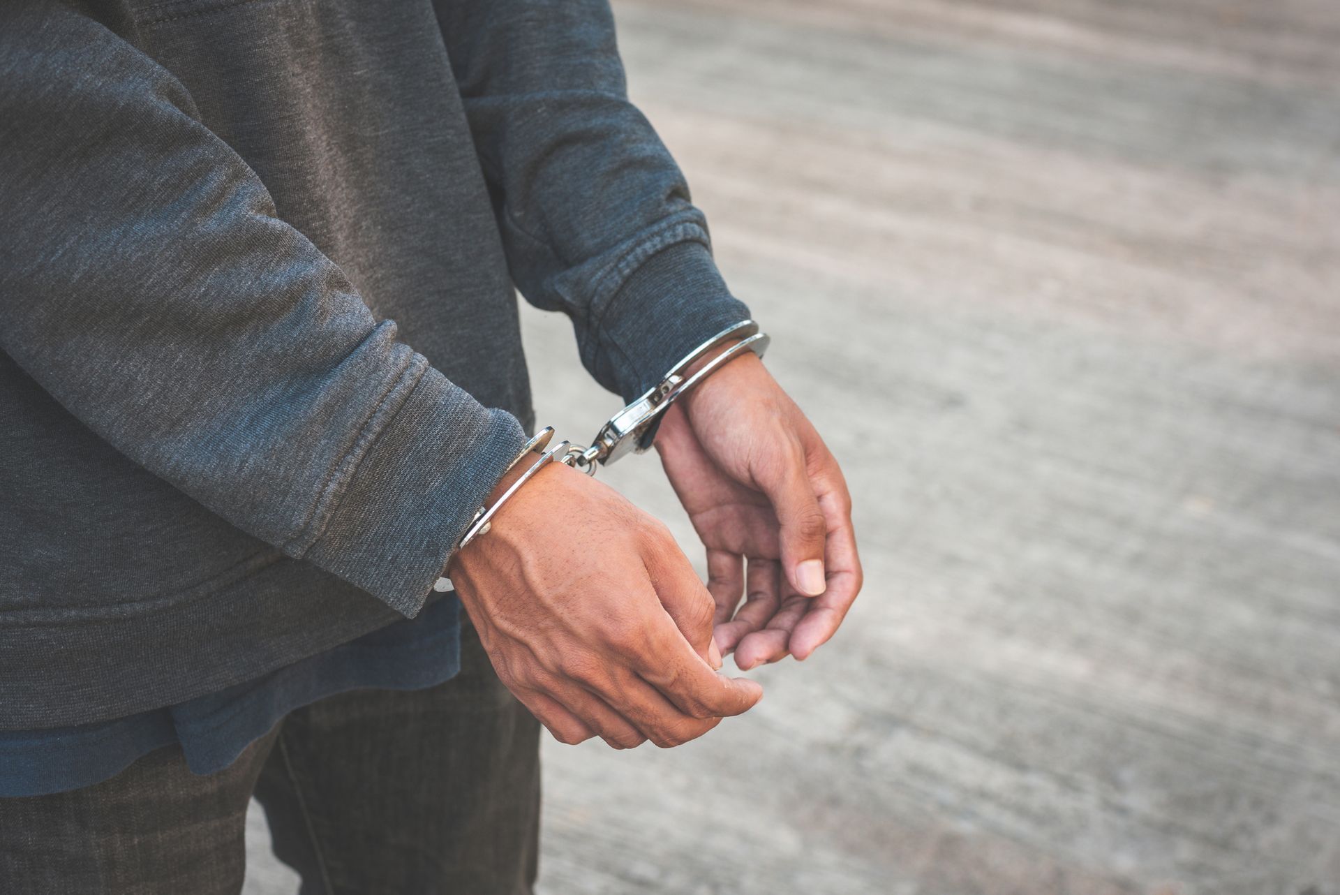 A close-up of an arrested man who is handcuffed.