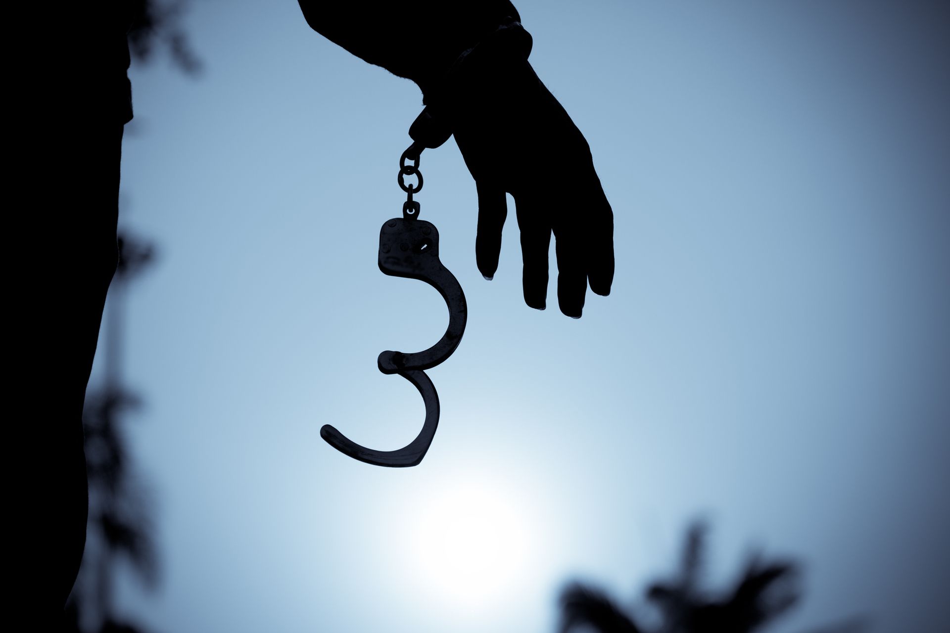 A silhouette of a person holding a pair of handcuffs