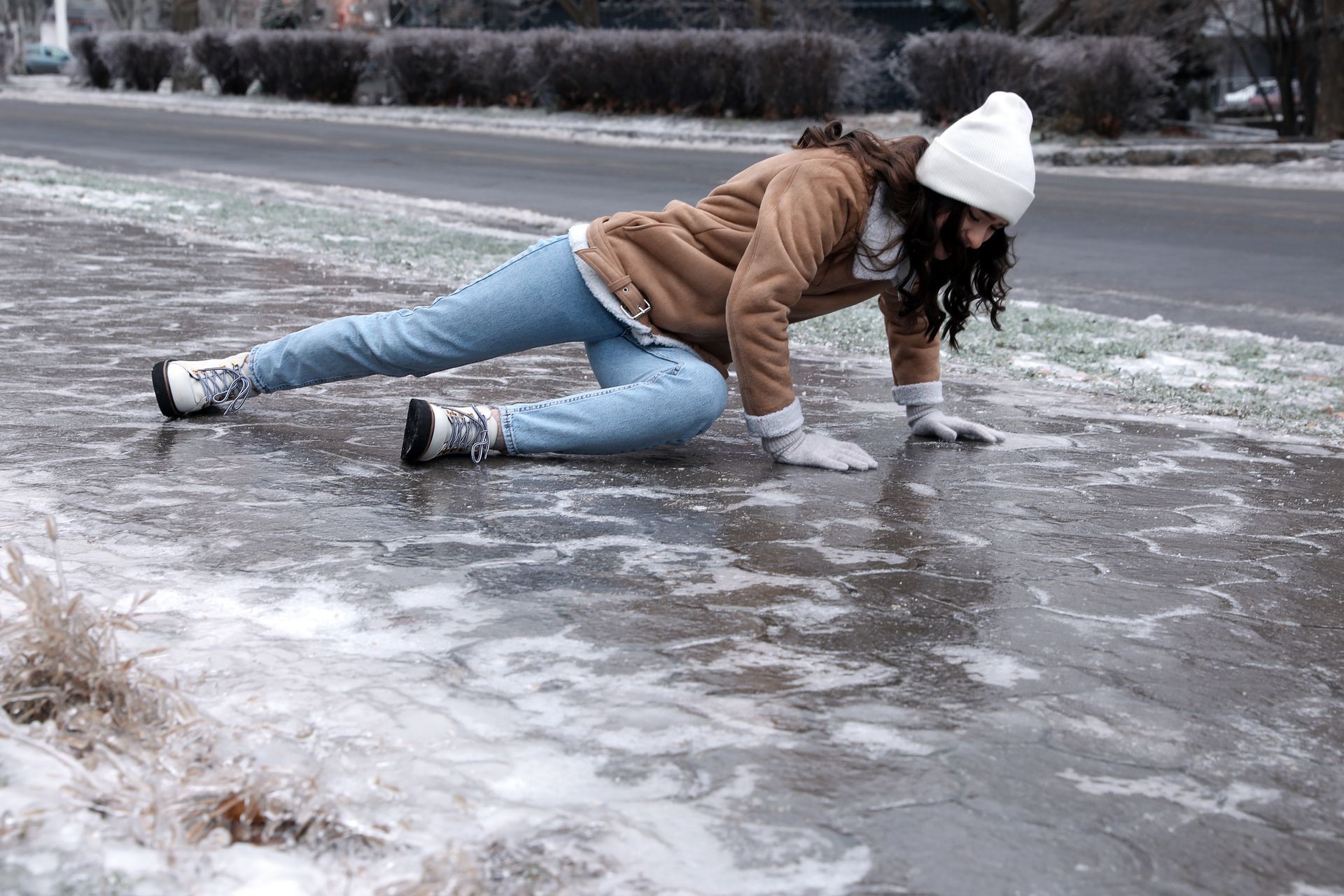 A woman is crawling on the ice on the side of the road.