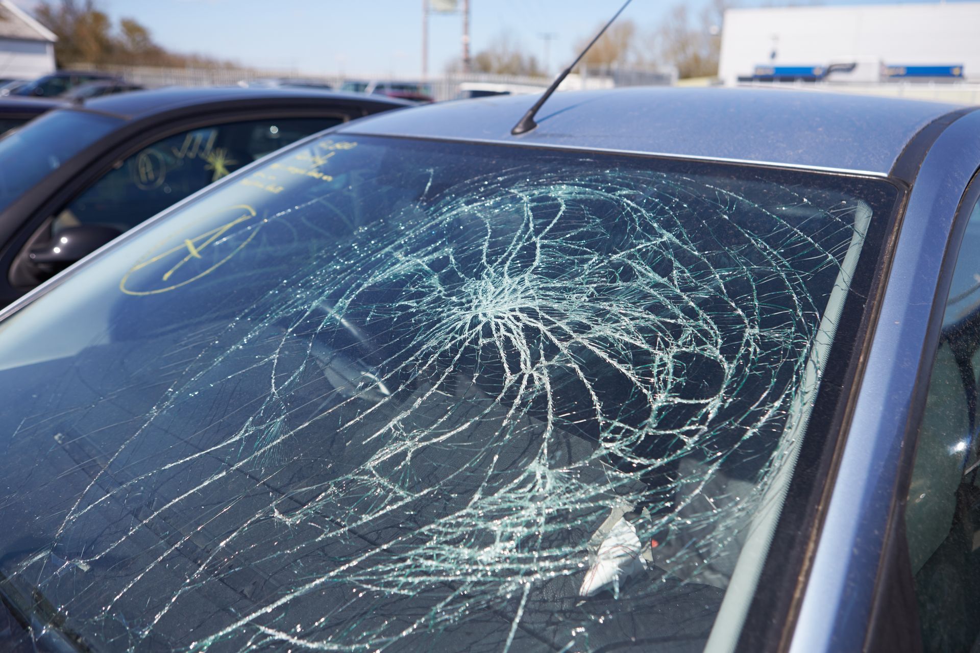 A car with a broken windshield is parked in a parking lot.
